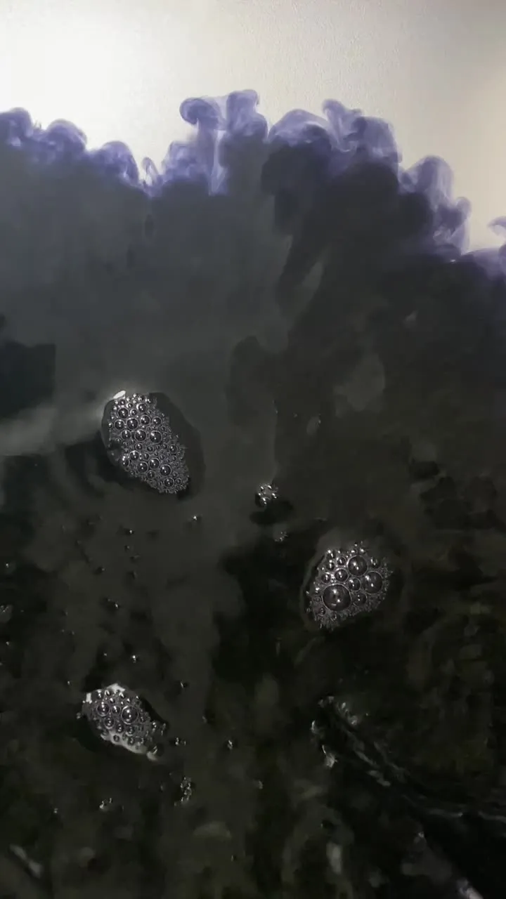 Dark dye spread through water in a steel tray